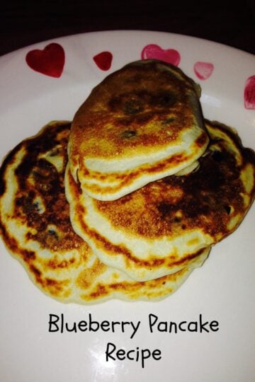 A plate stacked with delicious blueberry pancakes, ready to be devoured.