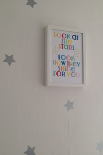 A grey and white stars nursery with a framed picture.