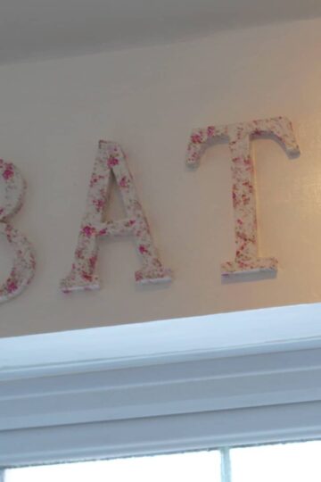 A shabby chic bathroom with the word bath hanging on the wall.