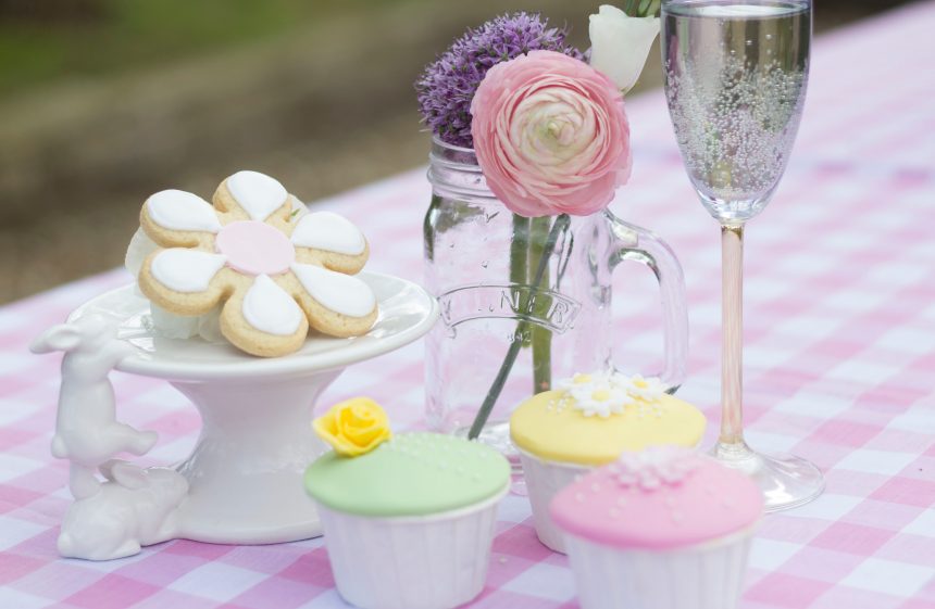 iced biscuits and cupcakes set out on a pink gingham tablecloth