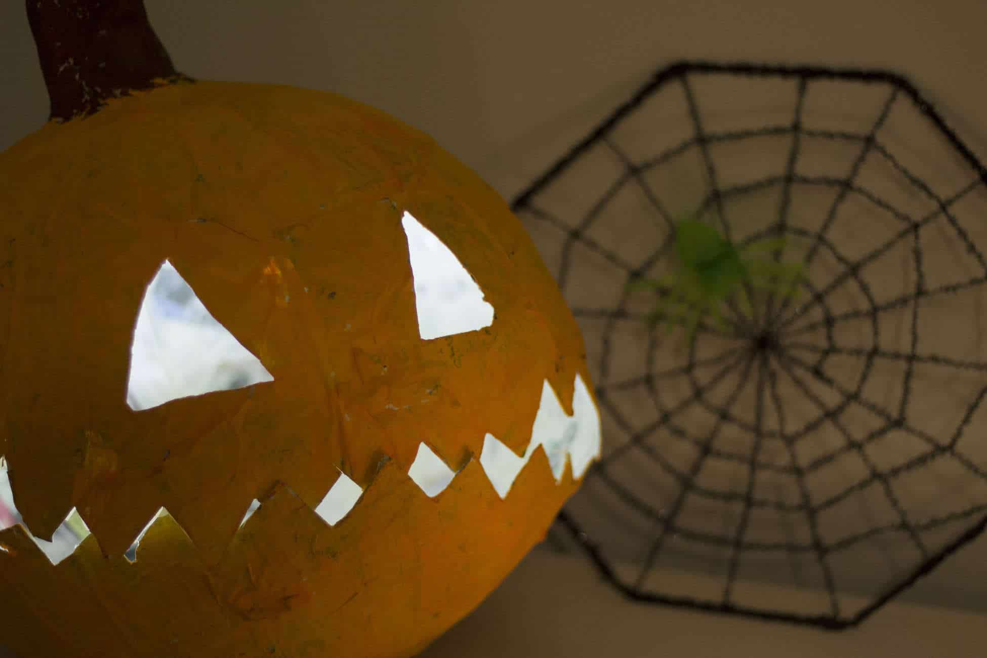 A carved pumpkin with a spider web on it, created using a paper mache tutorial.