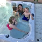 A family in a hot tub on a deck.