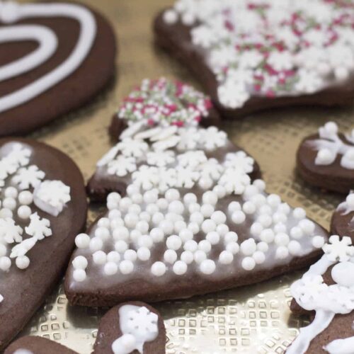 A tray of chocolate gingerbread cookies decorated with icing and snowflakes.