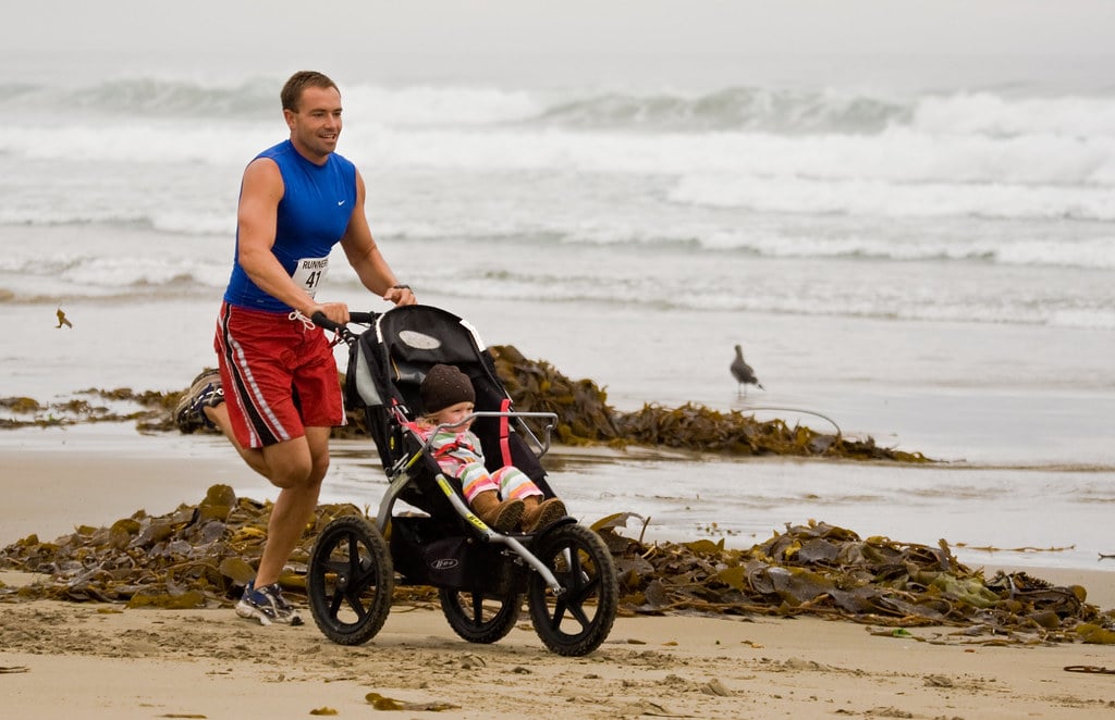 man running with a baby in a pushchair