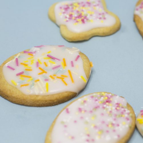 biscuits iced with white icing and decorated with sprinkles