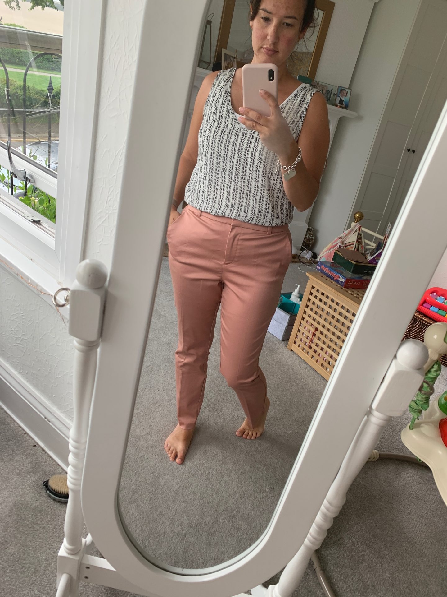 lady in pink cigarette trousers and a white and black patterned top