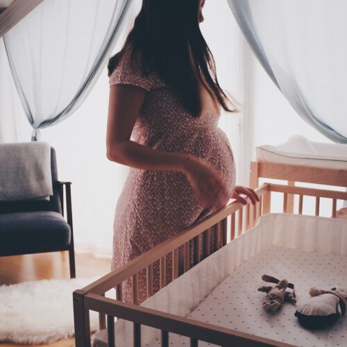pregnant woman standing over cot