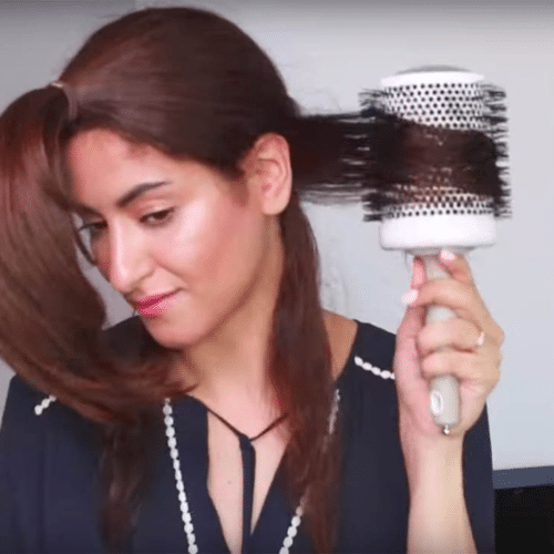 woman curling her hair with a brush.