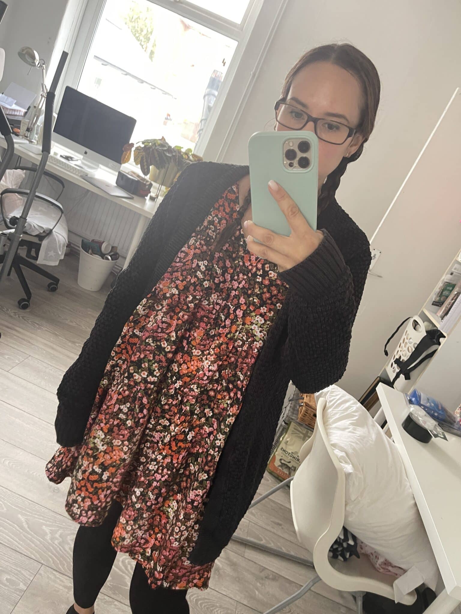 Ali wearing a dress that she bought on Vinted. The dress is black with pink flowers and she wears a black cardigan over the top. 