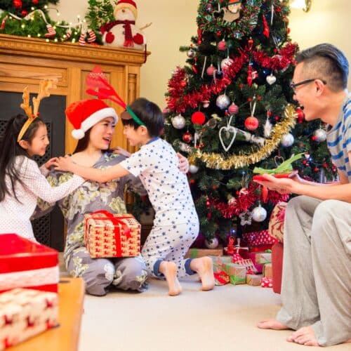 a family opening presents in front of a christmas tree