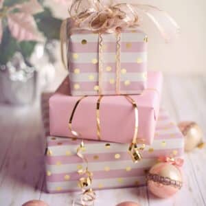 a stack of presents beautifully wrapped with pink and gold paper and tied with gold ribbon