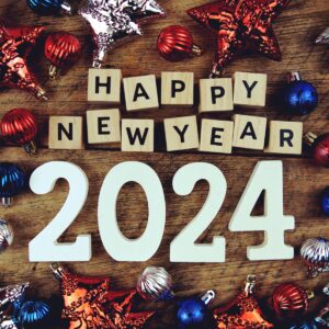 Happy new year's resolutions 2024 surrounded by ornaments on a wooden table.