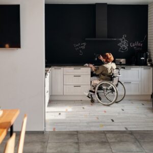 A woman with limited mobility in a wheelchair navigating her kitchen.