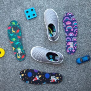 A group of children's shoes and toys, including sensory-friendly socks, laying on the floor in complete comfort.