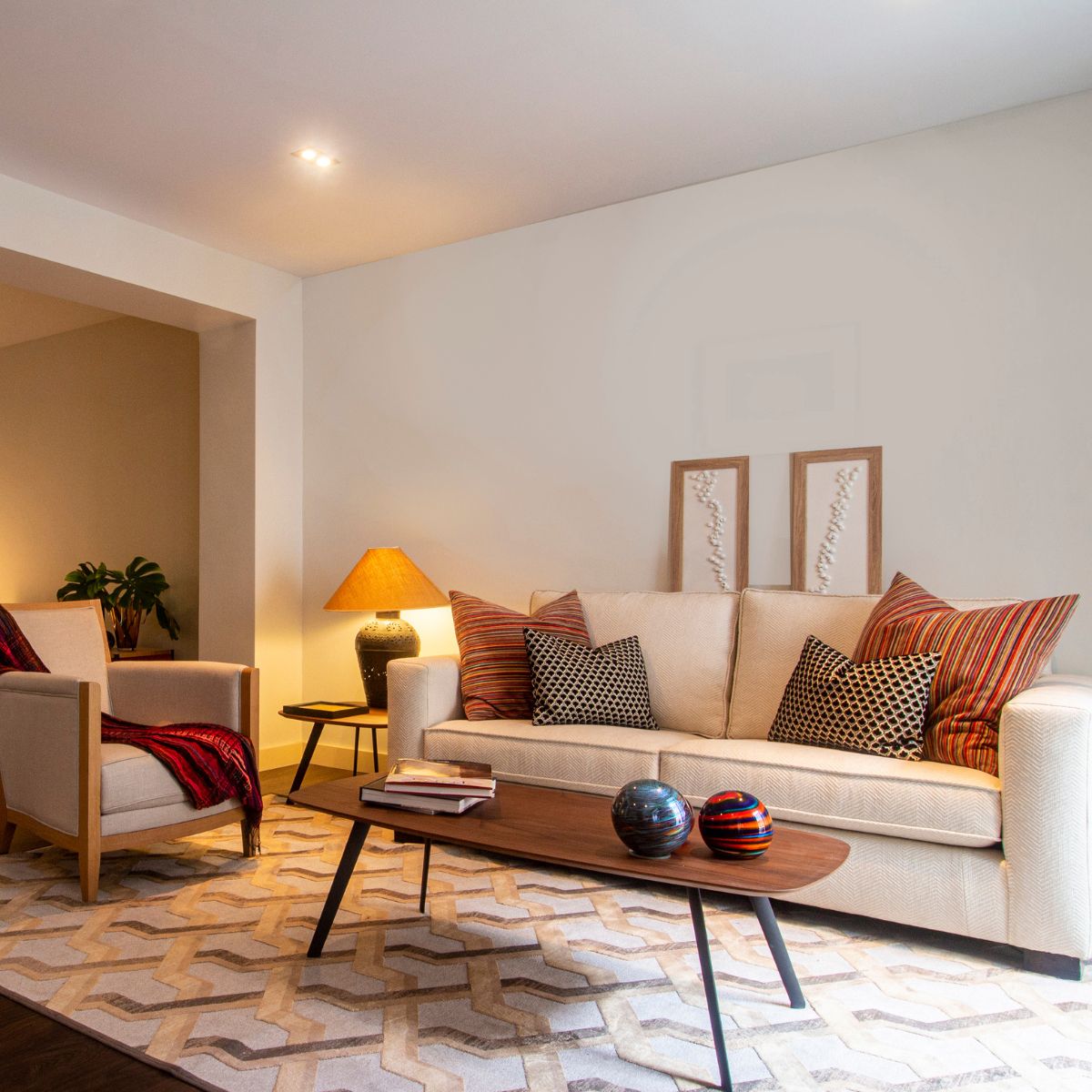 Contemporary living room with a timeless classic sofa, patterned cushions, a wooden coffee table, and decorative lamps.