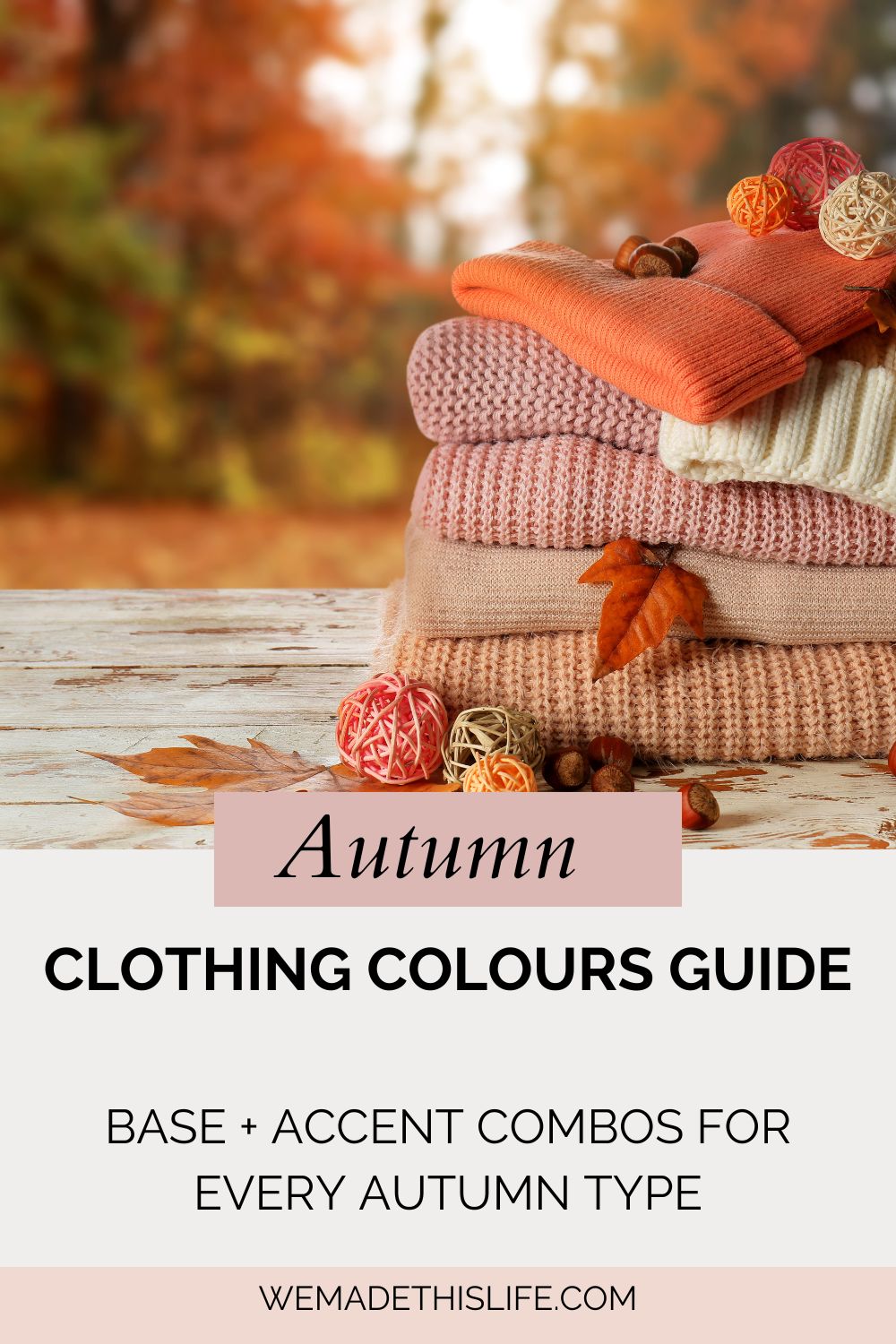 A stack of folded autumnal-coloured sweaters with decorative balls and leaves on top, set on a wooden surface with a blurred autumn foliage background. Text reads: "Autumn Clothing Colours Guide - Refresh Your Wardrobe.