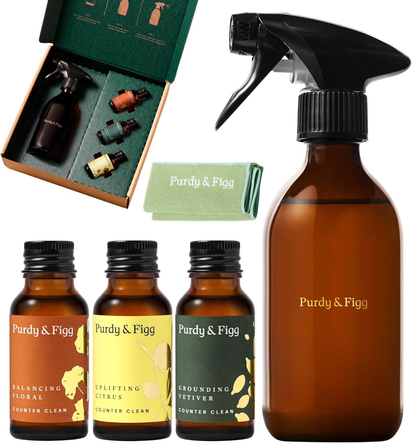 A Purdy & Figg cleaning set with an amber spray bottle, three labelled concentrate bottles, a green microfibre cloth, and a box displaying the products inside-perfect for tackling your kitchen cleaning checklist.