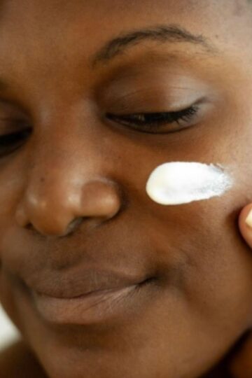 Person applying a dab of cream to their cheek with one finger, eyes closed, looking content as if they've discovered their new favourite product. It's part of a haul where everything's under £50, offering luxury without breaking the bank.