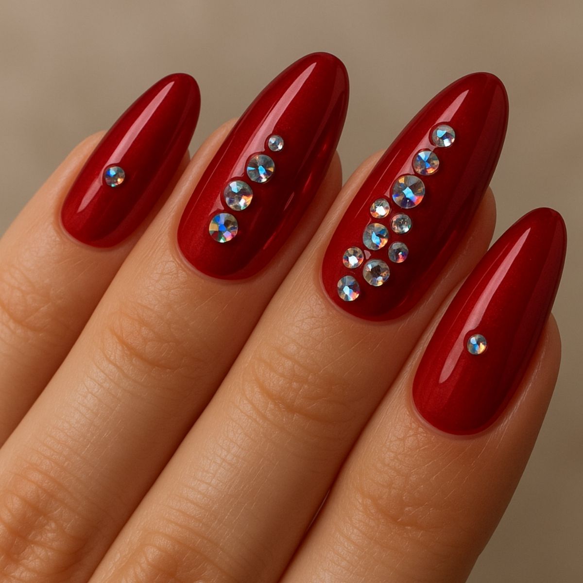 A hand with long, almond-shaped red nails features Crystal Nail Art, showcasing small, round, iridescent rhinestones arranged in lines and clusters for a dazzling effect.