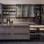 Modern kitchen with dark wood cabinets, wall cabinets, open shelving, potted plants, glass-front cupboards, a sink, and a large island with seating-combining style and the benefits of smart storage.