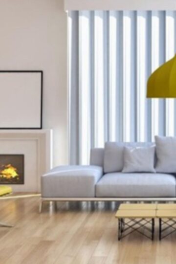 Modern living room with a gray sofa, yellow chair, yellow pendant lamp, coffee table, fireplace, and vertical motorized blinds—perfect for effortless smart home upgrades.