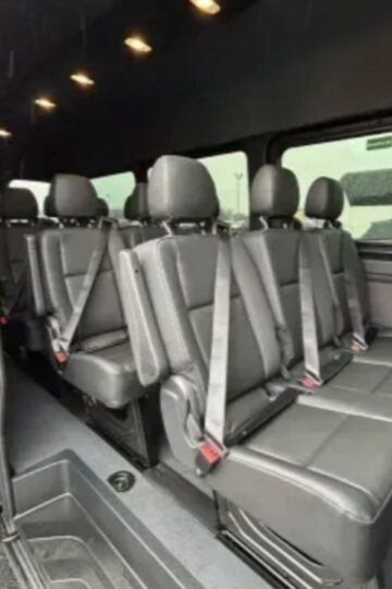 Interior of a Chicago touring bus with three rows of black leather seats, each equipped with seat belts, viewed from the open side door—perfect for your next group experience exploring Chicago wonders.