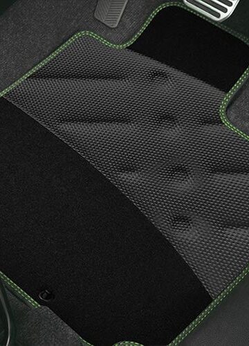 Black textured car floor mat with green stitching placed under metal accelerator, brake, and clutch pedals—ideal for those choosing car mats that combine durability and style.