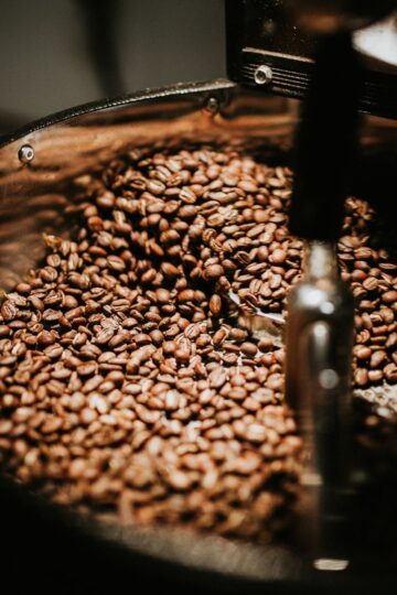 Close-up of coffee beans being stirred inside a metal drum, capturing the fresh roasting process in action.