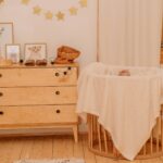 Curate a cozy nursery for your new baby with light wood accents, a dresser, animal artwork, star garland, and a round crib draped in a cream blanket. The soft, neutral color palette creates a serene space.