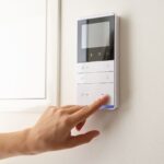 A person presses a button on a wall-mounted control panel with a display screen and several buttons-making energy-efficient upgrades to help lower heating bills.