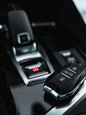 A car key fob rests on a shiny black surface near a modern automatic gear lever-ready for car transport or long-distance removals within the sleek vehicle interior.