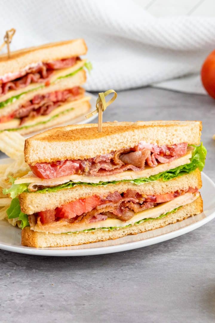 Celebrate With These Recipes for Lunch Ideas on Mother's Day A classic BLT sandwich with bacon, lettuce, tomato, and mayonnaise between toasted bread, cut in half and served on a white plate.