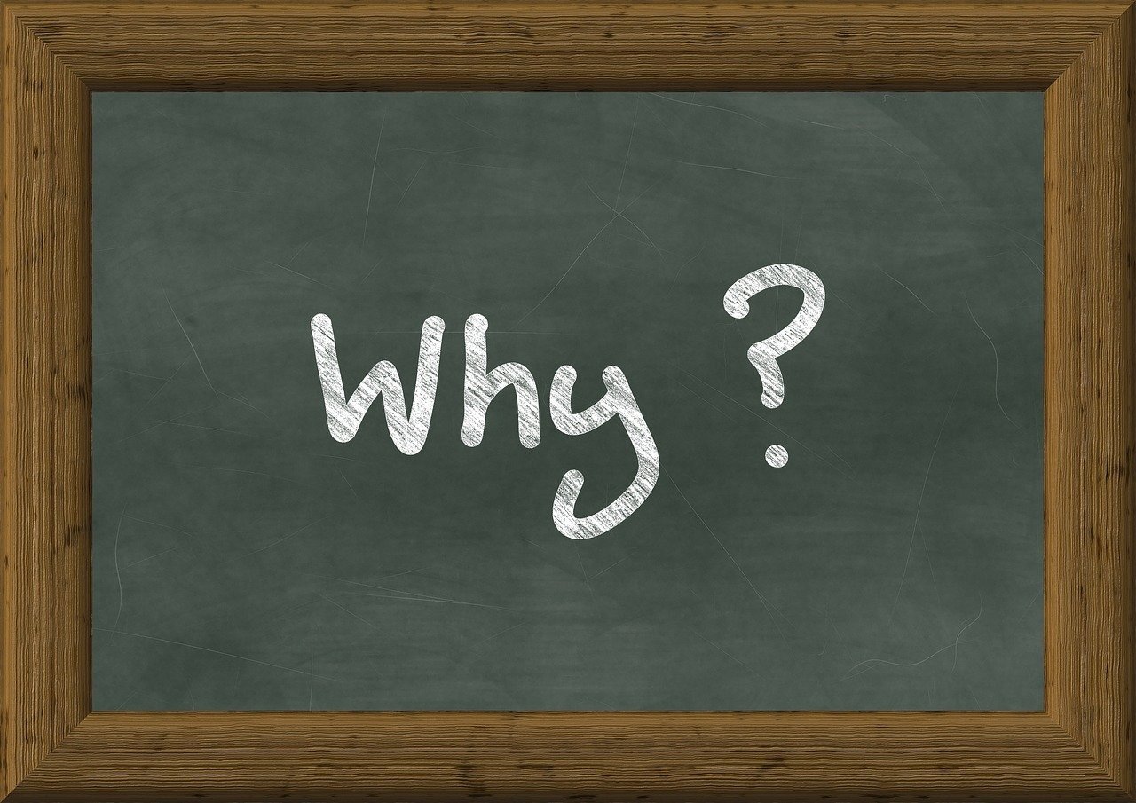 A blackboard with a wooden frame displays the word "Why?" written in white chalk in the centre.