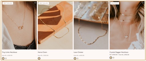 Four product images of gold necklaces are displayed with names and prices: Tiny Links Necklace, Herra Chain, Lace Choker, and sold-out Crystal Dagger Necklace.