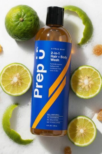 Bottle of Prep U 2-in-1 Hair + Body Wash with citrus mint scent, surrounded by halved limes, a whole lime, and dried citrus slices—an easy addition to your natural family bathroom for simple swaps towards a natural bathroom routine.