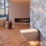 Modern bathroom with a wall-mounted toilet, bidets, freestanding bath, wood-patterned floor, stone feature wall, and a built-in fireplace-perfect to simplify family life with both style and comfort.