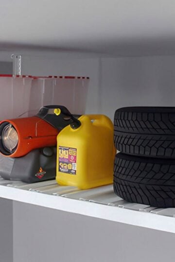 A metal storage shelf holds clear plastic bins, a red and black utility torch, a yellow petrol container, and two stacked car tyres—perfect for those looking to declutter home and keep family clutter under control.