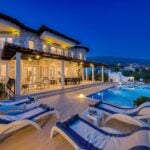 Luxury villa with stone exterior, outdoor terrace, swimming pool, sun loungers, and mountain views at dusk-perfect for high-end buyers seeking refined comfort and breathtaking ambience. Ideal property for targeted marketing to discerning clients.