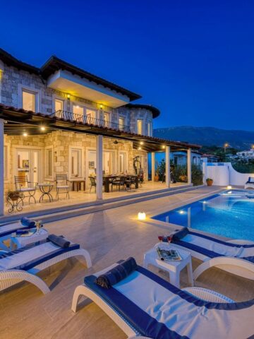 Luxury villa with stone exterior, outdoor terrace, swimming pool, sun loungers, and mountain views at dusk-perfect for high-end buyers seeking refined comfort and breathtaking ambience. Ideal property for targeted marketing to discerning clients.