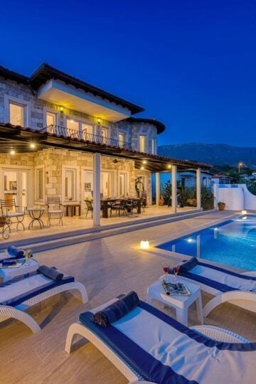Luxury villa with stone exterior, outdoor terrace, swimming pool, sun loungers, and mountain views at dusk—perfect for high-end buyers seeking refined comfort and breathtaking ambience. Ideal property for targeted marketing to discerning clients.