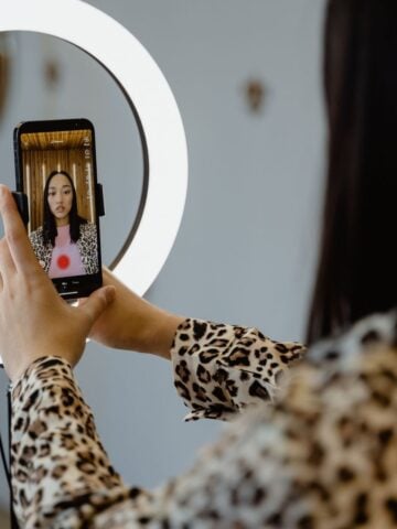 A person in a leopard-print top takes a selfie or films a video with a mobile phone and ring light, capturing the essence of 2026 TikTok growth trends among innovative TikTok creators.