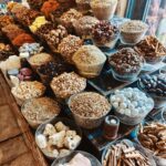 Glass bowls filled with various dried herbs, spices, and roots are arranged on shelves in a market or shop-perfect for those looking to buy organic products or stock up on organic in bulk at Vehgroshop.