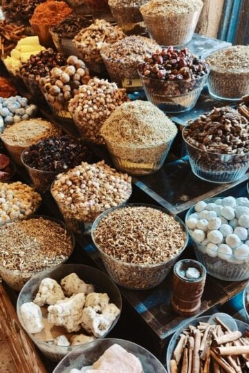 Glass bowls filled with various dried herbs, spices, and roots are arranged on shelves in a market or shop—perfect for those looking to buy organic products or stock up on organic in bulk at Vehgroshop.