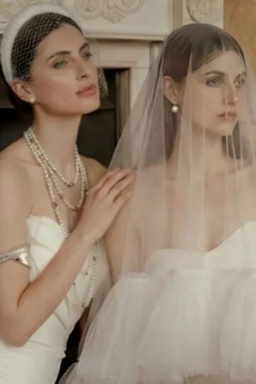Two women in white strapless Missacc Wedding Dresses; one wears a pearl necklace and headband, the other has a veil over her face. Both are seated indoors, exuding quality that’s truly worth your money as they look away from the camera.