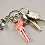 A close-up of a keyring holding several keys, including a prominent red key and a silver replacement filing cabinet key, resting on a light surface.