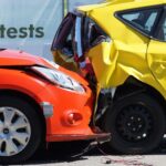 A red car has rear-ended a yellow car, causing significant damage to both vehicles in what appears to be a crash test demonstration, similar to scenarios often seen when making car accident claims.