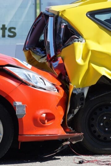 A red car has rear-ended a yellow car, causing significant damage to both vehicles in what appears to be a crash test demonstration, similar to scenarios often seen when making car accident claims.