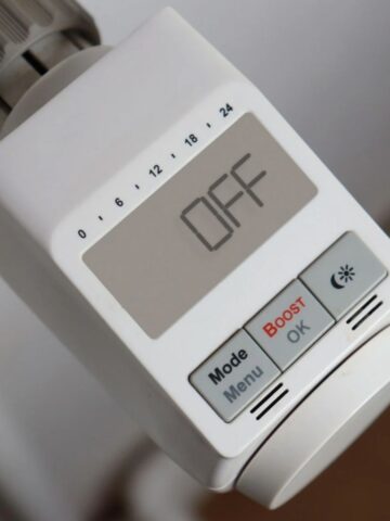 Close-up of an electronic thermostat display showing "OFF," with buttons labelled Mode, Menu, Boost, OK, and a sun icon-an essential tool for effective home heating.