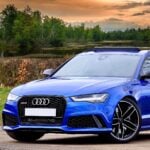 A blue Audi sports car parked outdoors near a lake with trees and a sunset sky in the background, highlighting the importance of regular tyre maintenance for optimal performance, especially when driving an Audi A3 with high-quality tyres.