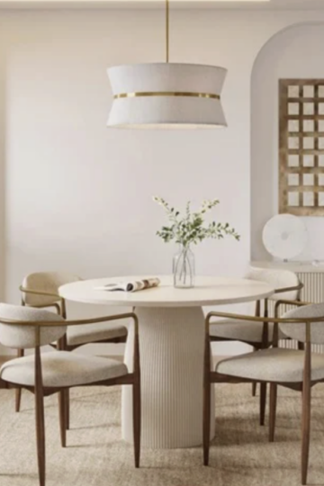 Shop Dining Tables at Modani: Elevate Your Dining Space with Modern Design A modern dining space featuring a round white dining table, four upholstered chairs, a pendant light, potted plant, and decorative items on a sideboard against a beige wall.